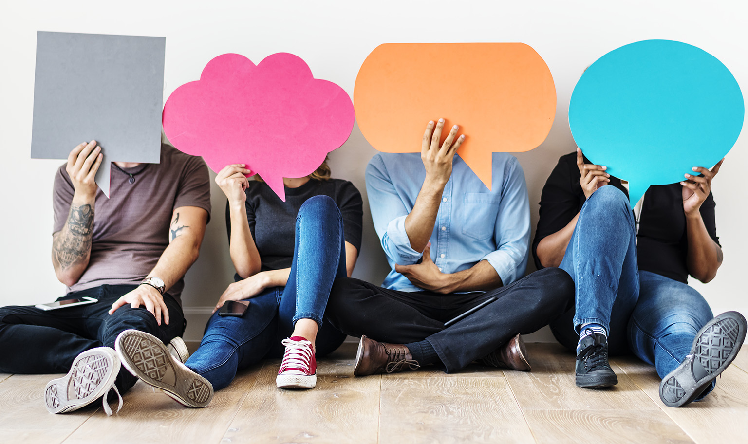 A diverse group of people holding speech bubbles in front of their faces